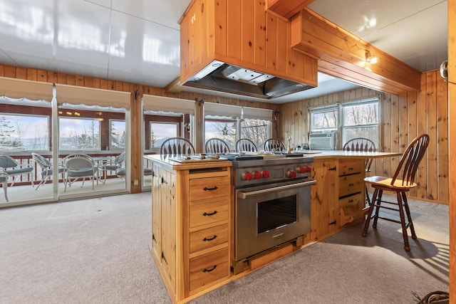 kitchen with premium range, light carpet, custom exhaust hood, kitchen peninsula, and wood walls