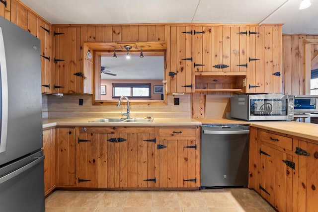 kitchen with stainless steel appliances, tasteful backsplash, sink, and wood walls