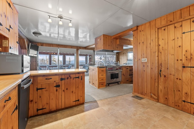 kitchen featuring wall oven, kitchen peninsula, and wood walls