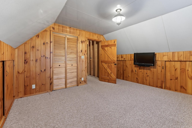 bonus room with vaulted ceiling, carpet floors, and wood walls