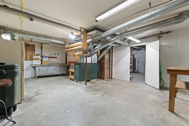 basement featuring heating unit and white fridge