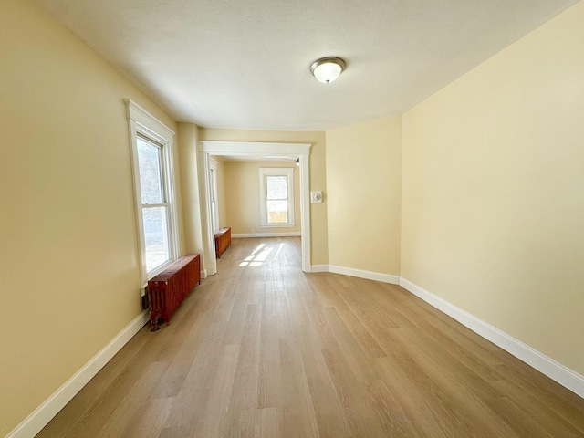 empty room with radiator heating unit and light hardwood / wood-style floors