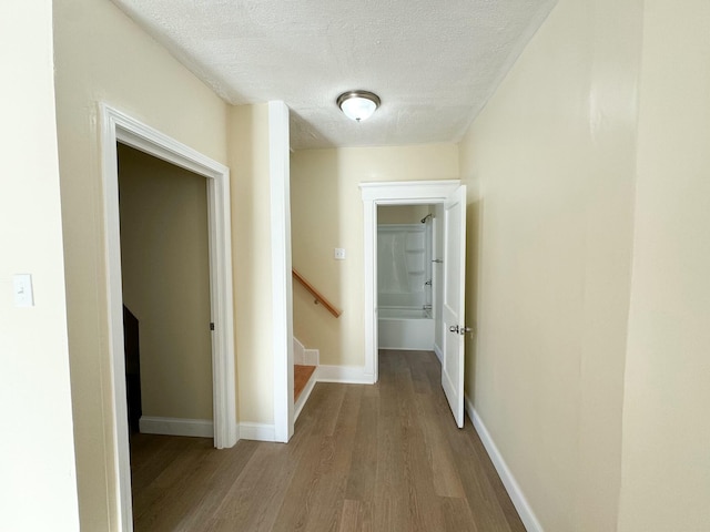 hallway featuring a textured ceiling and light hardwood / wood-style flooring