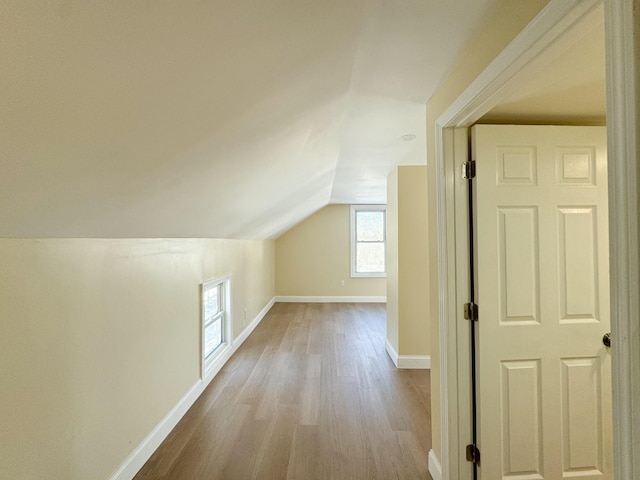 additional living space featuring vaulted ceiling and light wood-type flooring