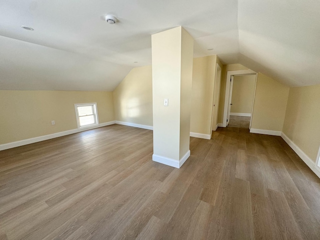 additional living space featuring vaulted ceiling and light hardwood / wood-style floors