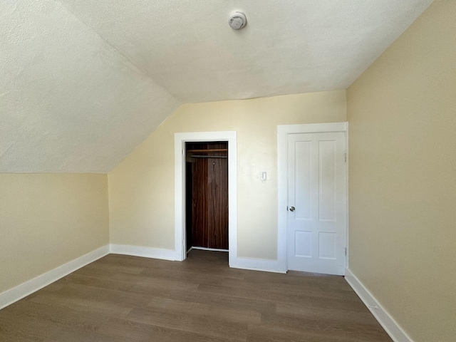 additional living space with hardwood / wood-style flooring, vaulted ceiling, and a textured ceiling