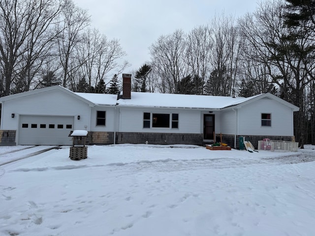 snow covered house featuring a chimney and a garage