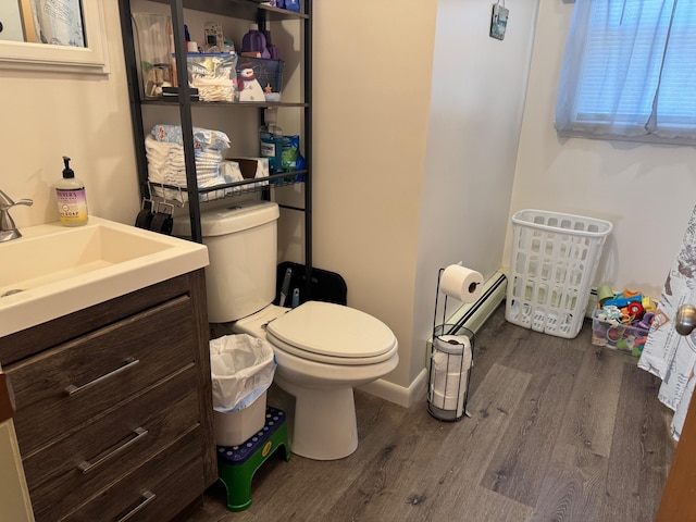 half bathroom featuring toilet, vanity, baseboards, and wood finished floors