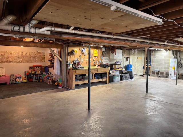 unfinished basement with concrete block wall, a workshop area, and water heater