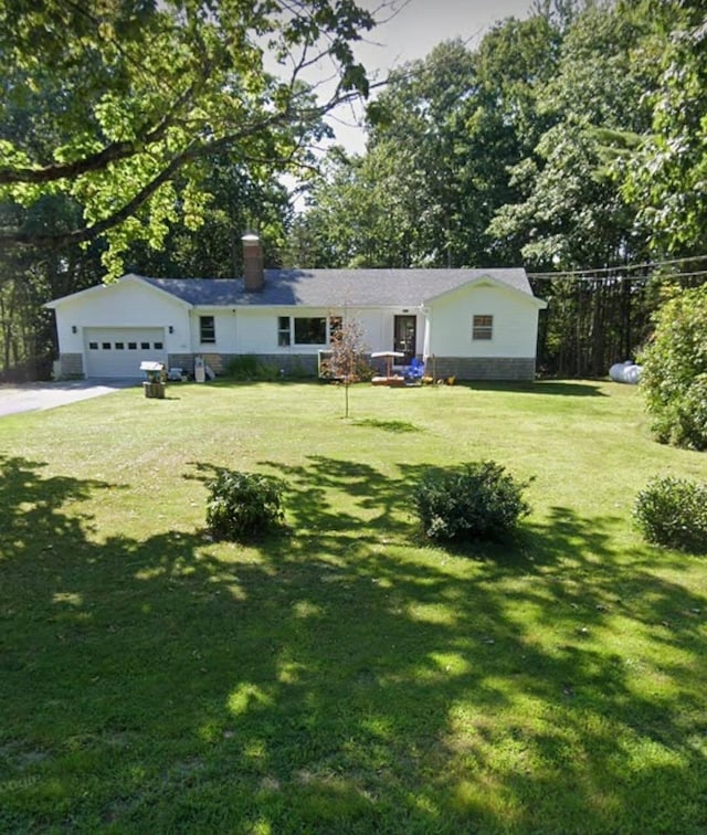 exterior space with a garage, driveway, a chimney, and a front yard