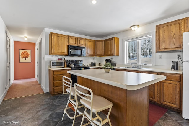 16 Hanna Ln, Bristol, ME 04539 - kitchen featuring black appliances, brown cabinetry, a sink, light countertops, and a kitchen bar