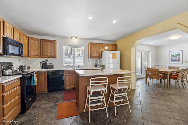 16 Hanna Ln, Bristol, ME 04539 - kitchen with black appliances, a kitchen island, a breakfast bar area, a sink, and light countertops