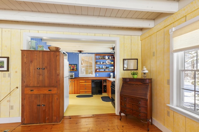 hallway with hardwood / wood-style flooring, wooden walls, and beam ceiling