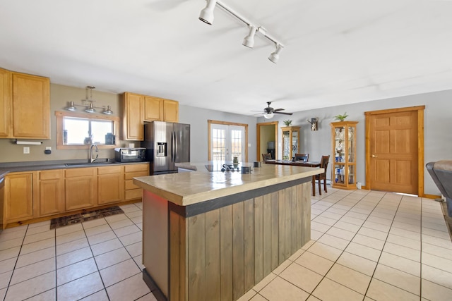 kitchen featuring a kitchen island, sink, light tile patterned floors, stainless steel refrigerator with ice dispenser, and french doors