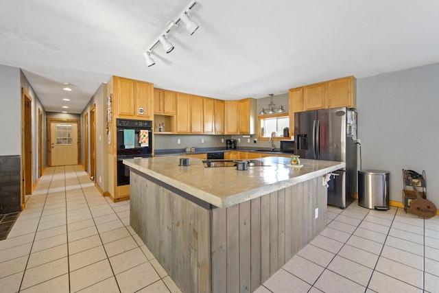 kitchen with sink, light tile patterned flooring, black appliances, and a kitchen island