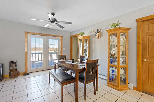 dining space featuring light tile patterned flooring, a baseboard heating unit, ceiling fan, a water view, and french doors