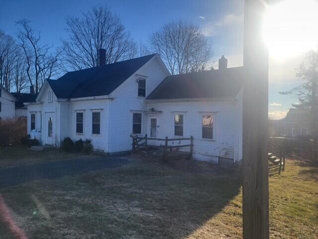 rear view of house featuring a lawn and a chimney