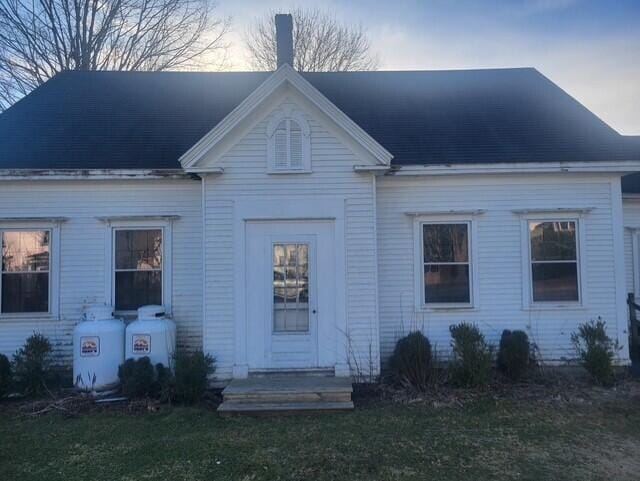 view of front of home with roof with shingles and a yard