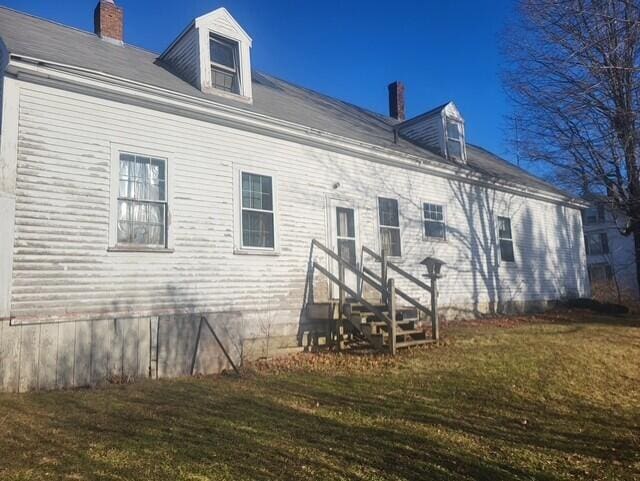 back of house with a lawn and a chimney