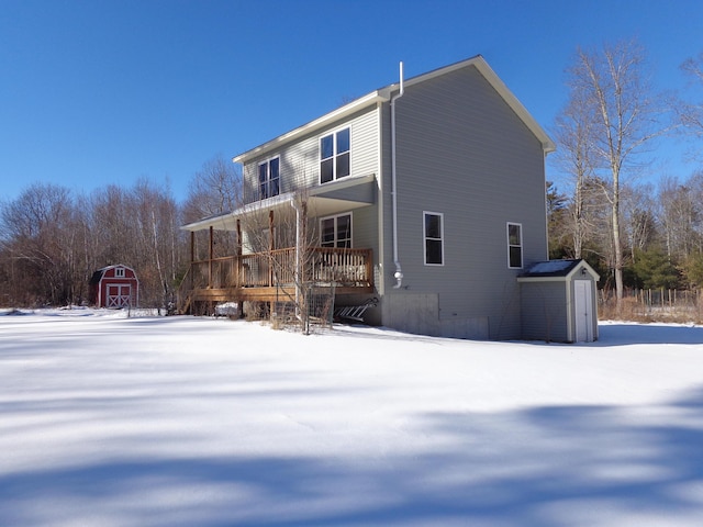 snow covered back of property with a storage unit