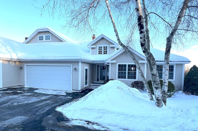 view of front of house with a garage, a chimney, and aphalt driveway