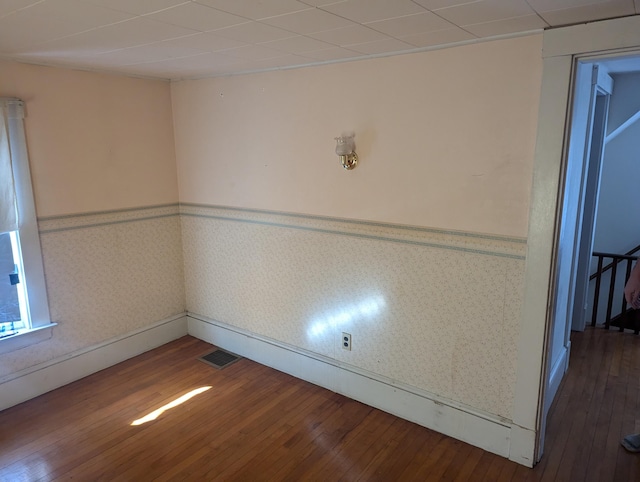 spare room with a wainscoted wall, visible vents, hardwood / wood-style flooring, and wallpapered walls