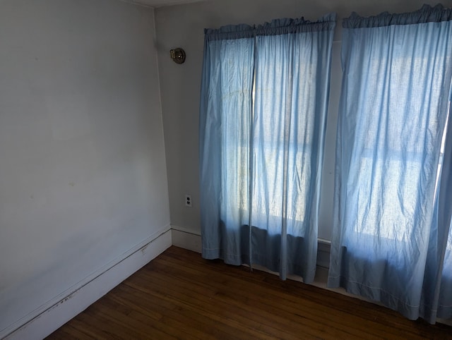 empty room featuring a baseboard heating unit and wood finished floors