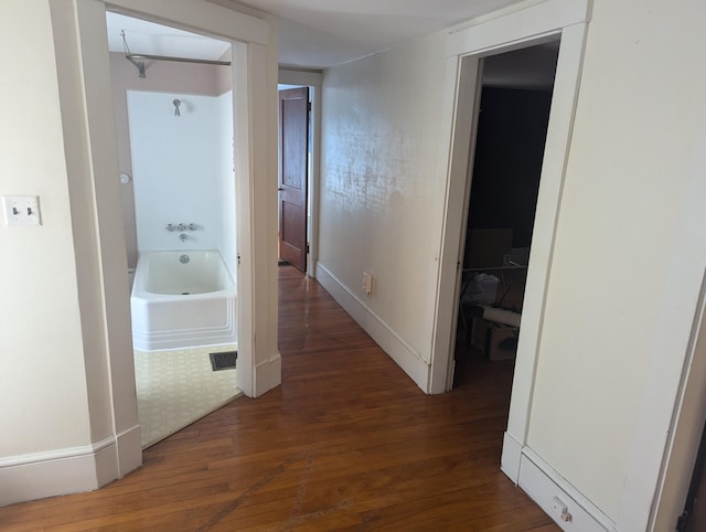 corridor with baseboards and hardwood / wood-style flooring