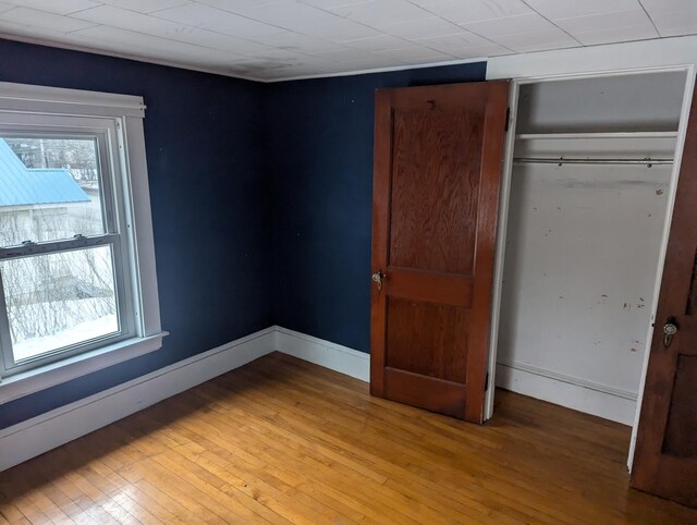 unfurnished bedroom with a closet, baseboards, multiple windows, and light wood finished floors