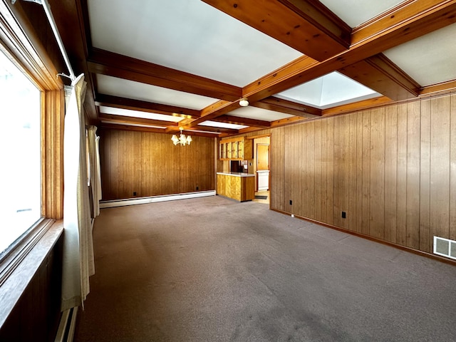 unfurnished living room with a baseboard radiator, wooden walls, carpet flooring, a notable chandelier, and beam ceiling