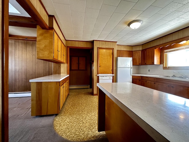 kitchen with fridge, a baseboard radiator, wooden walls, and sink