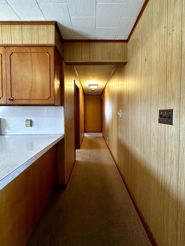 corridor with light colored carpet and wood walls