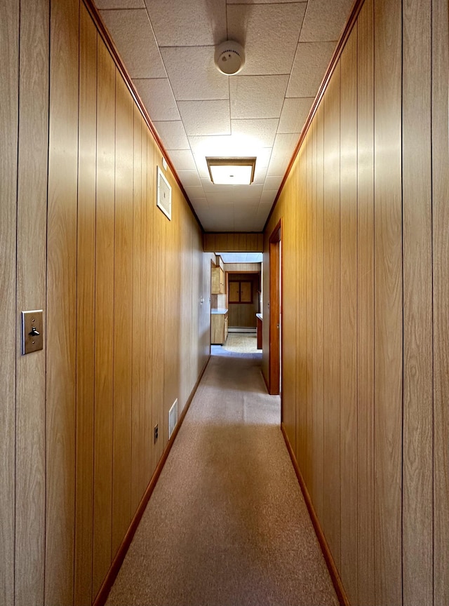 hall featuring wooden walls and light colored carpet