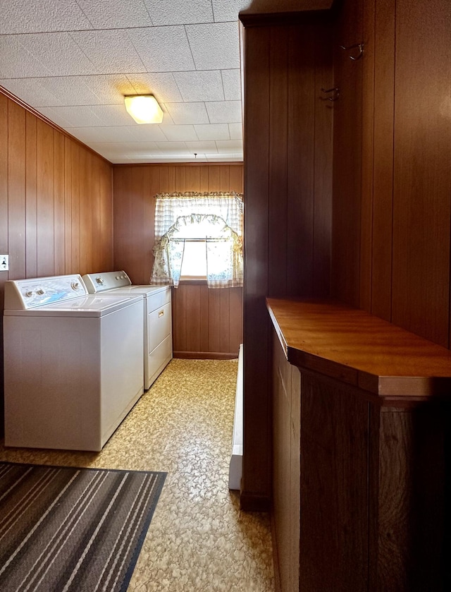 clothes washing area with independent washer and dryer and wood walls