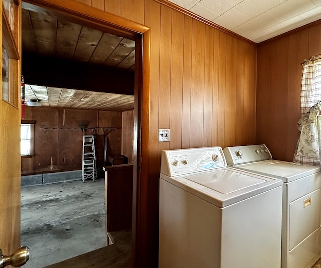 clothes washing area with wooden walls and washing machine and clothes dryer