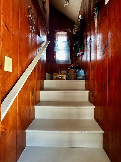 stairs with wooden walls and vaulted ceiling