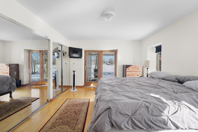 bedroom featuring access to exterior, french doors, multiple closets, and light wood-type flooring