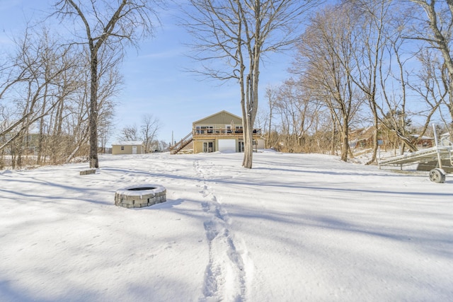 snowy yard with a wooden deck and an outdoor fire pit