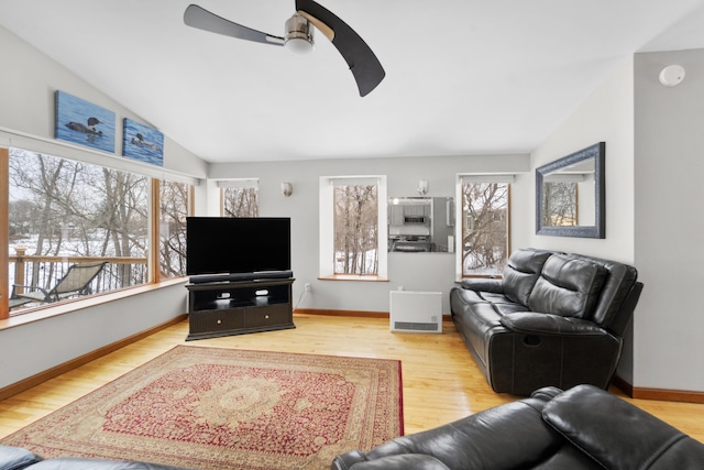 living room with ceiling fan, light hardwood / wood-style floors, and vaulted ceiling