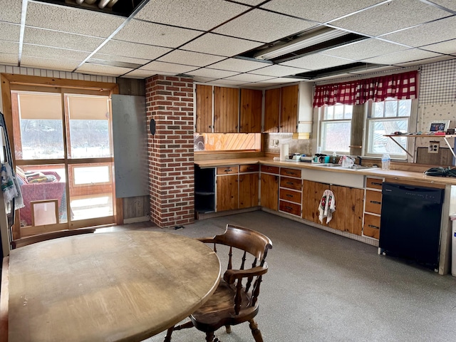 kitchen with a drop ceiling, sink, wooden walls, and dishwasher