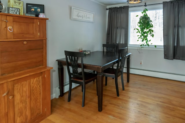 dining space featuring a baseboard radiator, ornamental molding, and light hardwood / wood-style flooring