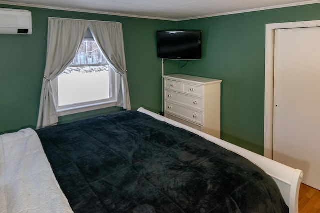 bedroom with crown molding, hardwood / wood-style flooring, and an AC wall unit