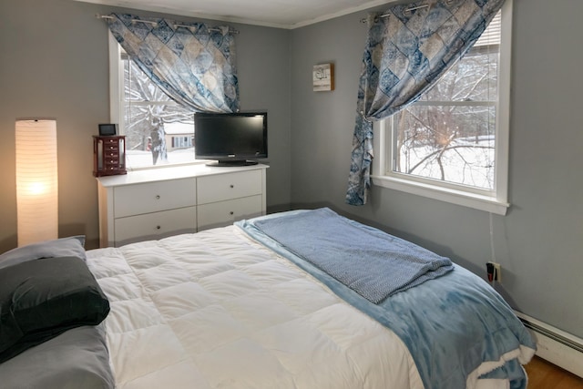 bedroom with a baseboard radiator, hardwood / wood-style floors, and crown molding