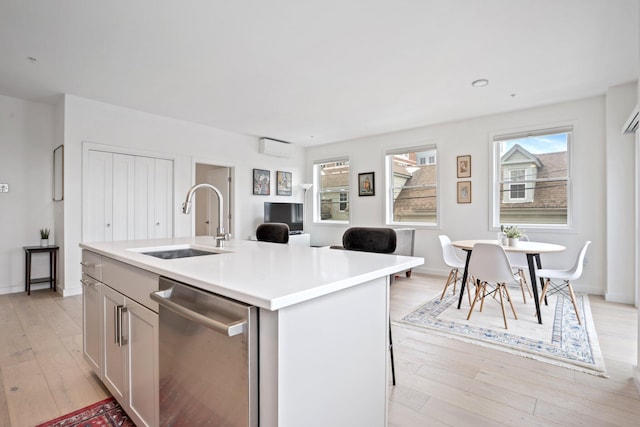 kitchen with dishwasher, light countertops, light wood-type flooring, and a sink