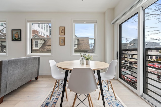 dining area with baseboards, light wood finished floors, and a healthy amount of sunlight