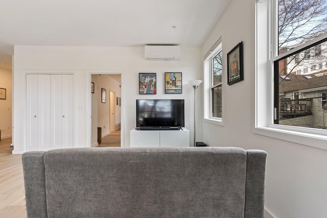 living room featuring a wall unit AC and light wood-style flooring