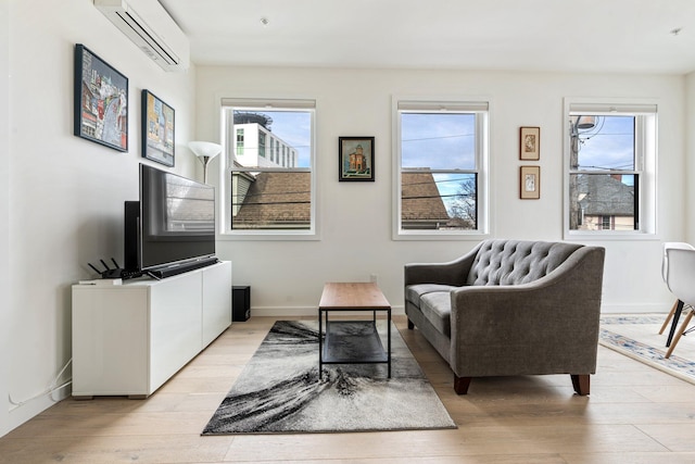 living area featuring a wall unit AC, light wood-style flooring, and baseboards