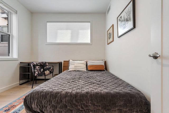 bedroom with baseboards, visible vents, and wood finished floors