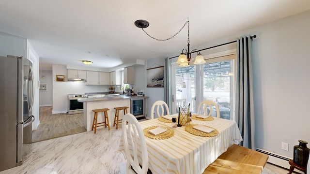 dining room with a baseboard heating unit, sink, a notable chandelier, and beverage cooler