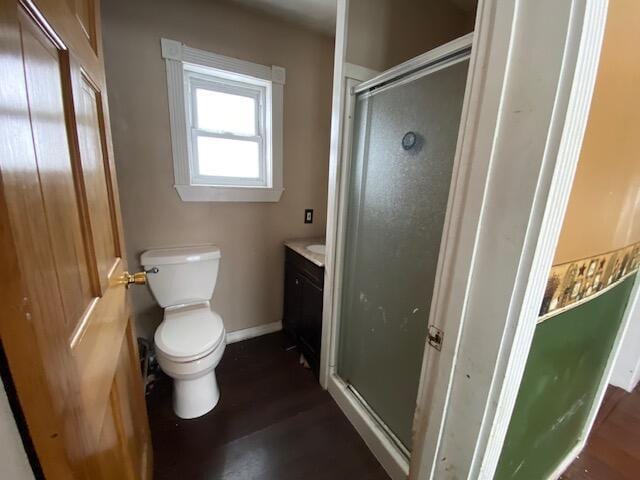 bathroom with hardwood / wood-style flooring, vanity, a shower with shower door, and toilet